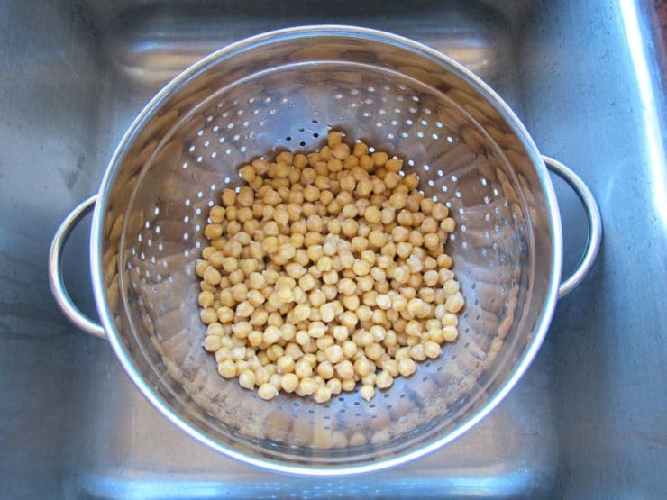 Draining chickpeas in colander in sink after soaking.