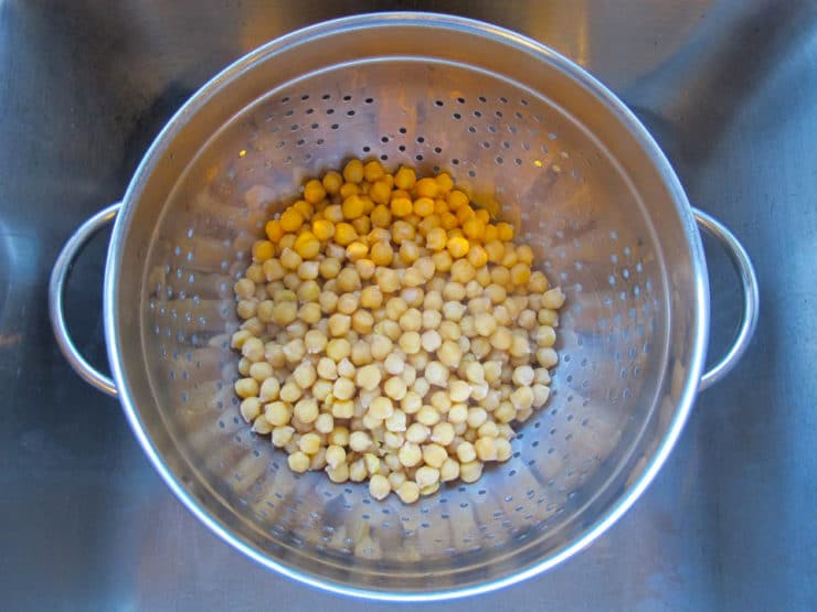 Cooked chickpeas drained in colander over sink.