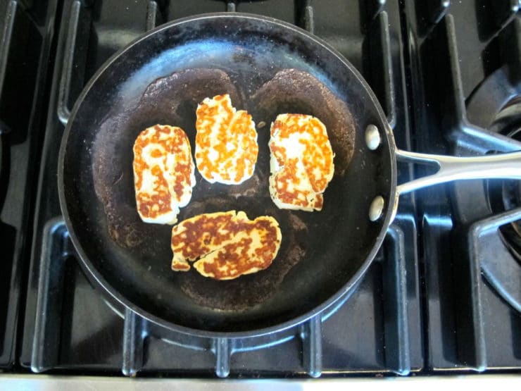 Halloumi cheese frying in a skillet.