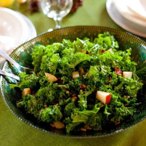 A colorful salad featuring kale, sliced pears, and dried cranberries on a white plate