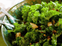 Fresh kale, pear, and cranberry salad with nuts and almonds in a green bowl