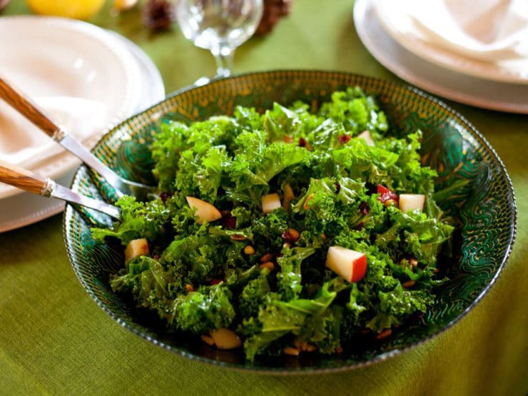 A colorful salad featuring kale, sliced pears, and dried cranberries on a white plate