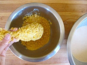 Dredging chicken parts in crushed cornflakes.