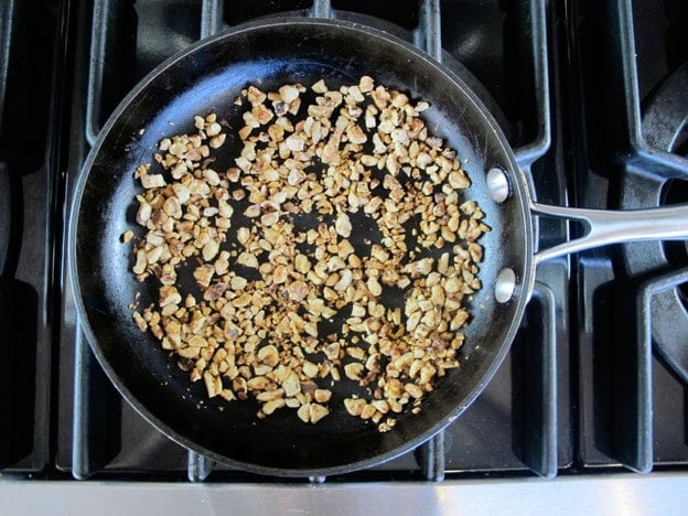 Dry toasting chopped walnuts in a skillet.