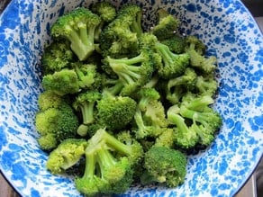Steamed broccoli florets in a colander.