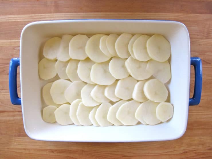 Sliced potatoes in a greased baking dish.