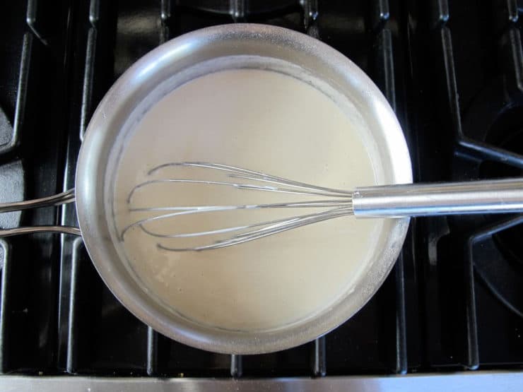 Whisking coconut milk into a roux.