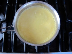 Heating a white sauce in a saucepan.