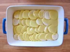 Sliced potatoes layered in a baking dish.