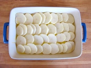 Sliced potatoes layered in a baking dish.