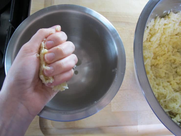Squeezing shredded potatoes.
