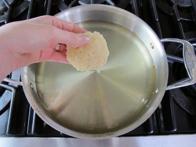 Carefully adding latke to oil.