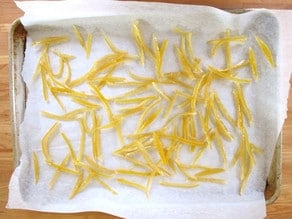 Lemon peels drying on a parchment lined baking sheet.