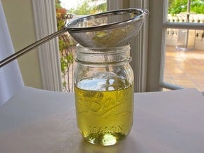Straining lemon simple syrup into a jar.