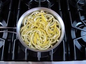 Lemon peels in simple syrup in a saucepan.
