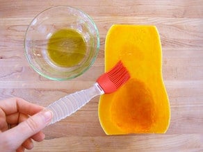 Brushing butternut squash with olive oil.