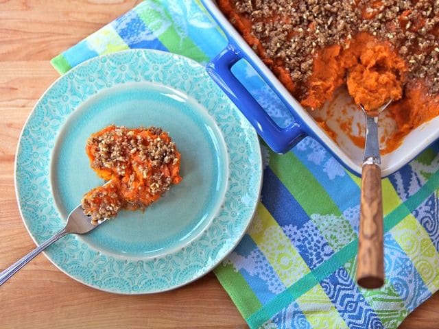 Slice of Nutty Sweet Potato Casserole on a blue fancy plate with a silver fork