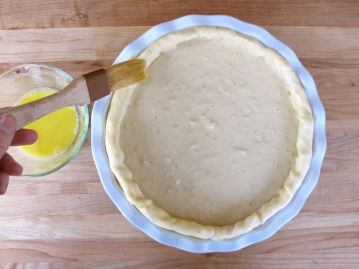 Brushing egg wash onto pie crust edges.