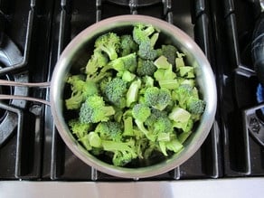 Raw broccoli in a pot of water.