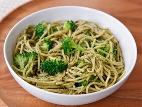 A delicious broccoli pasta, topped with flavorful broccoli and pesto sauce served on a white plate