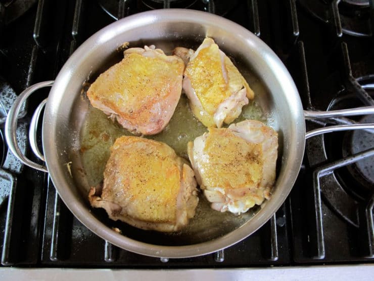 Browning chicken thighs in a skillet.