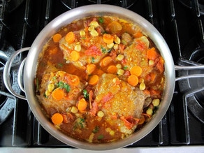 Chicken thighs added to stew in saucepan.