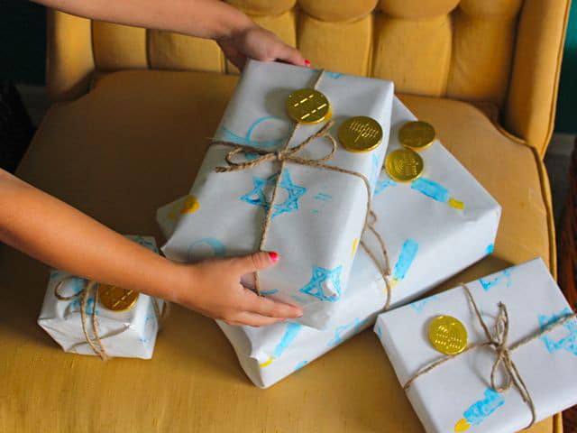 Young hands holding gifts wrapped with homemade holiday gift wrap.