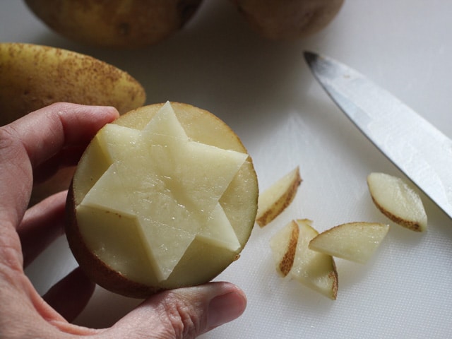 hand holding potato stamp carved with star of David.
