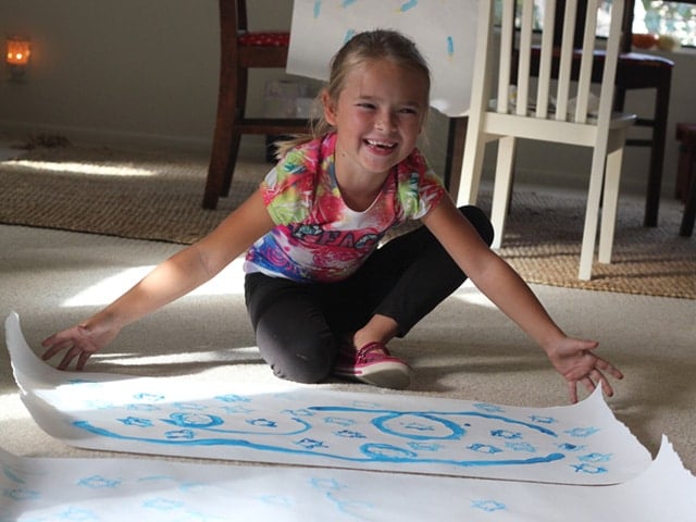 Girl presenting her homemade stamped gift wrap paper. 