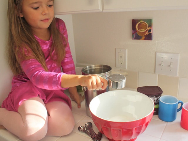 Measuring hot cocoa mix ingredients into a bowl.