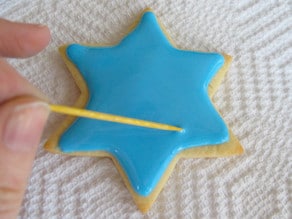 Decorating star of David sugar cookie. Popping bubbles in blue icing with toothpick.