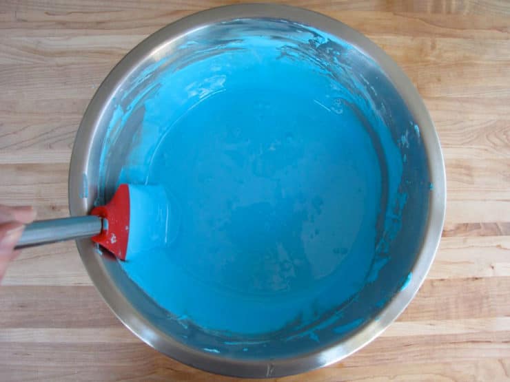 Stirring blue icing with spatula.