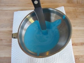 Pushing icing through funnel into bottle with spatula.