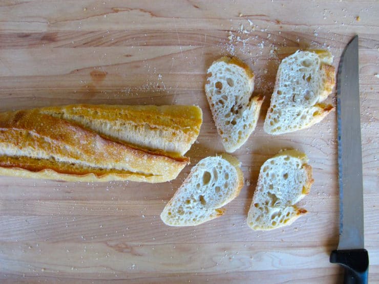 Thinly slicing a baguette.