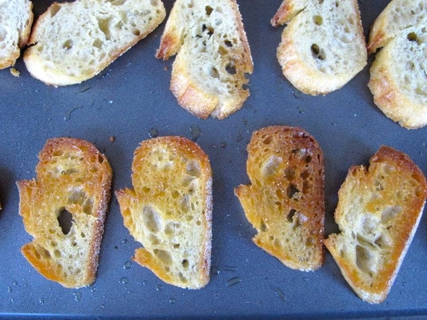 Toasted crostini on a baking sheet.