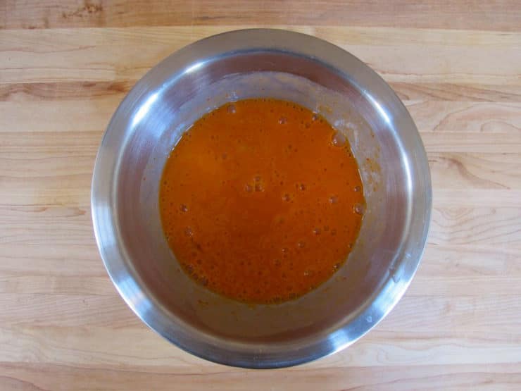 Eggs and hot sauce whisked in a bowl.