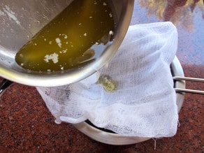 Straining clarified butter through cheesecloth.