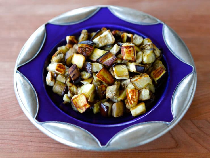 Purple plate with roasted eggplant slices on the countertop