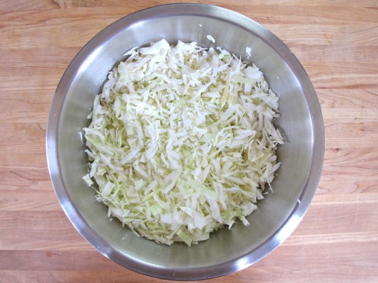 A close-up photo of a cabbage chopped into tiny pieces tightly packed together in a bowl