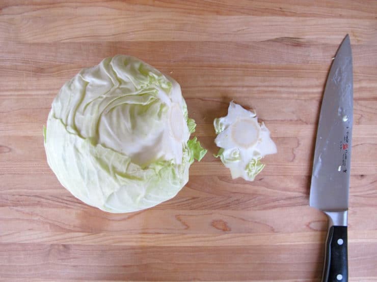 A cabbage and knife on a cutting board