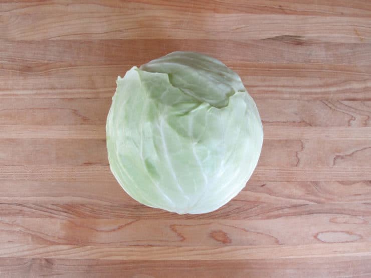 A whole cabbage on a wooden cutting board