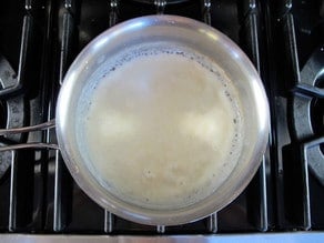 Milk added to a roux in a saucepan.