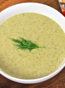 A bowl of Creamy Broccoli Tahini Soup garnished with a dill sprig