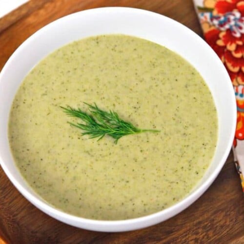 A bowl of Creamy Broccoli Tahini Soup garnished with a dill sprig