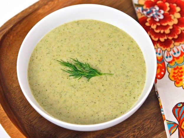 A bowl of Creamy Broccoli Tahini Soup garnished with a dill sprig.