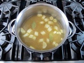 Chopped potatoes in broth in a stockpot.