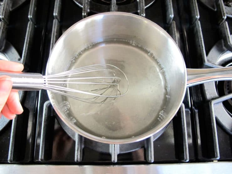 Whisking sugar into boiling water.