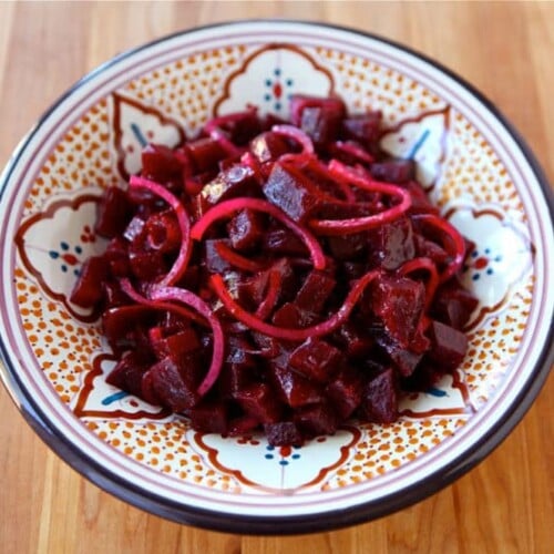 Roasted Beet and Red Onion Salad served in a plate with design on top of a wooden table