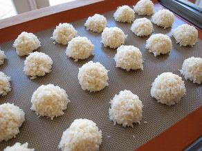Coconut macaroons lined up on a silpat covered baking sheet.