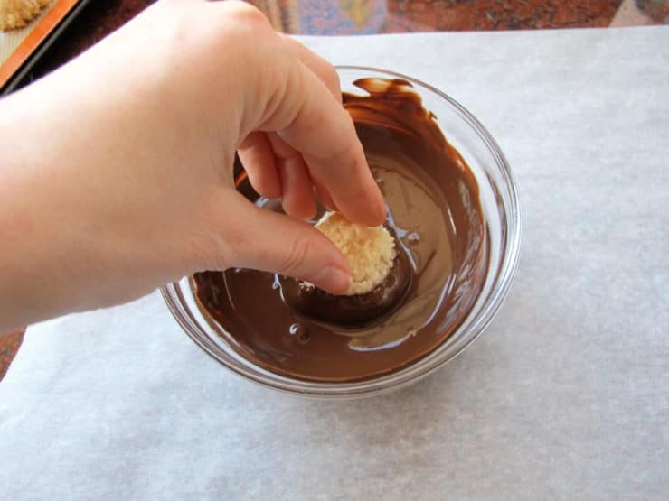 Dipping coconut macaroons into melted chocolate.